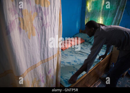 I teacher and running coach at a girls school in rural Southern Ethiopia makes his bed before heading off to work. Stock Photo