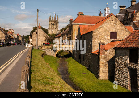 Scenic view of a stream running through the market town of Helmsley in North Yorkshire with the parish church in the background Stock Photo