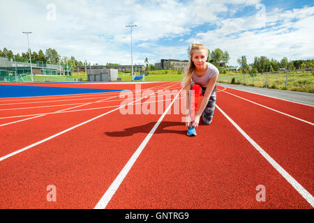 Confident Woman Tying Shoelace On Running Tracks Stock Photo