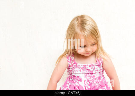 Closeup Portrait of Beautiful Toddler Girl Looking Down on Neutral Background Stock Photo