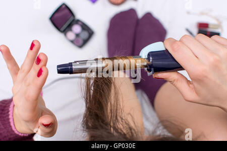 Woman using curling iron on her hair point of view Stock Photo