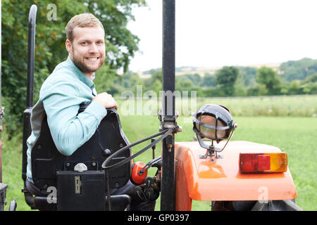 Portrait Of Farmer Sitting On Tractor In Field Stock Photo