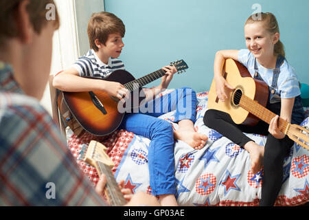 Children In Bedroom Playing Guitars Together Stock Photo