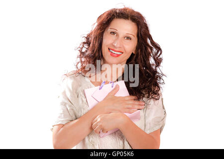 Pretty mature woman wearing a creamy dress holding and hugging a gift bag Stock Photo