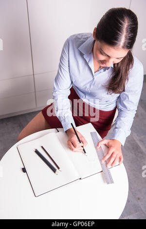 top view of young female engineer drawing into notebook Stock Photo