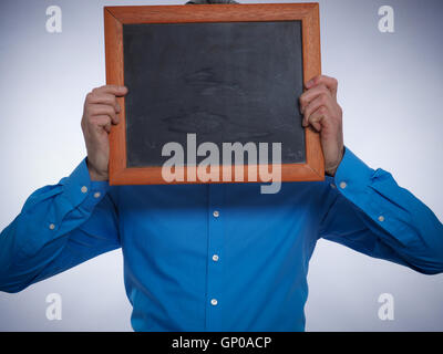 Businessman hiding his face behind a small chalkboard with space for text or image Stock Photo