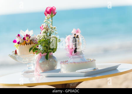 table setting for wedding, wedding cake with doll weds, pink roses in vase, seasoning fruit. Stock Photo