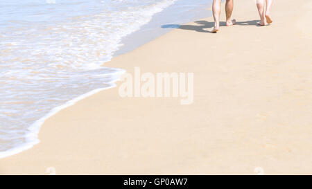 Couples walking on tropical sandy beach in vacations. Shadow on sand. Stock Photo