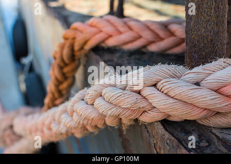 Ropes on Old Rusty Ship Closeup. Old Frayed Boat Rope as a Nautical Background. Naval Ropes on a Pier. Vintage Nautical Knots. Stock Photo