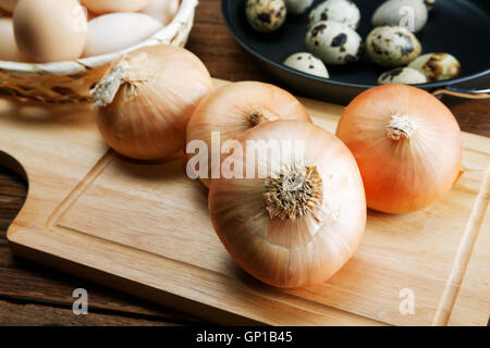 Still life with onions and quail eggs on a kitchen table Stock Photo
