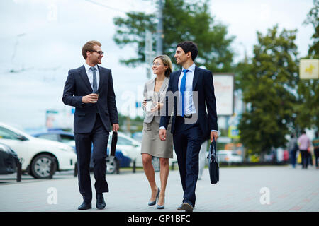 Three colleagues walking down city street after working day Stock Photo