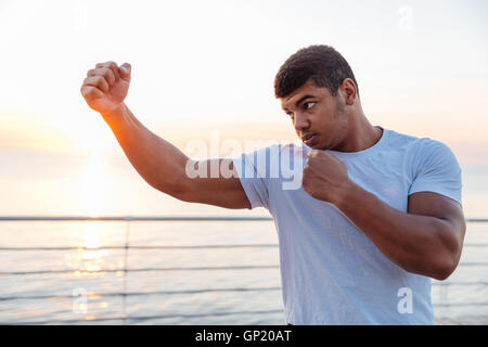 Concentrated african american young man boxer working out outdoors on sunrise Stock Photo