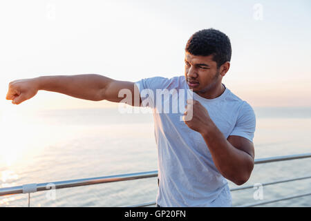 Muscular african american young sportsman standing and doing exercises outdoors Stock Photo