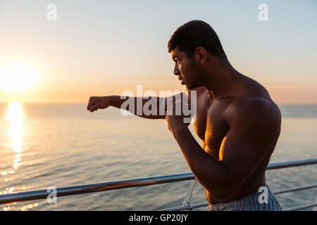 Silhouette of african american young man athlete practicing shadow boxing at sunrise Stock Photo