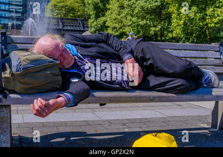 Elderly man, homeless sleeping on park bench Stock Photo
