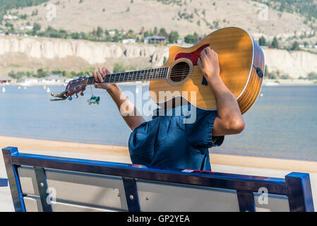 man playing guitar upside down behind his head Stock Photo