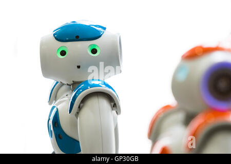 Small robots with human face and body - humanoid. Artificial Intelligence - AI. Orange and blue robots isolated on white backgro Stock Photo