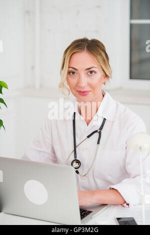 Portrait Of Happy Young Female Doctor Working On Computer at her office Stock Photo