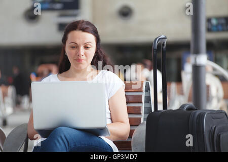woman with laptop in airport, using internet connection, traveler checking email Stock Photo