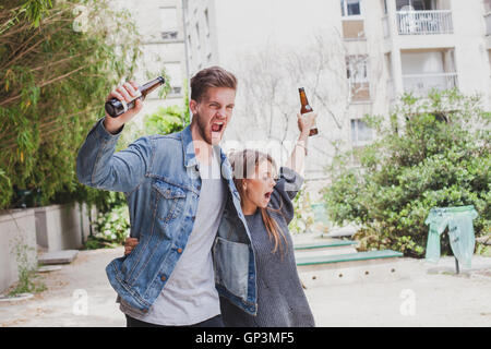 drunk people singing on the street, young couple with beers Stock Photo