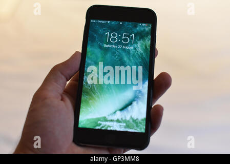 Apple reveal new iOS 10. Mans hand holding iphone, phone in mans hand Stock Photo