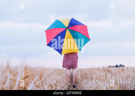 woman with colorful umbrella in the field, optimistic positive multicolored background with copyspace Stock Photo