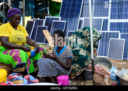 BURKINA FASO, Provinz Poni, Gaoua, weekly market with food crops and solar panels, girl playing with mobile phone /Gaoua, Markt, Verkauf Erdnuesse, Bohnen, Reis, Stand mit Solar Modulen, Maedchen mit Mobiltelefon Stock Photo