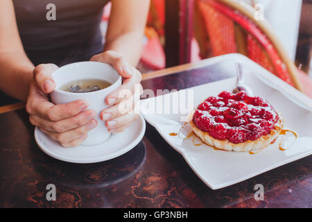 drinking tea with sweet dessert in cafe, close up of hands with cup and fruit cake Stock Photo