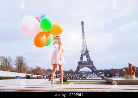 happy girl with multicolored balloons near Eiffel tower in Paris Stock Photo