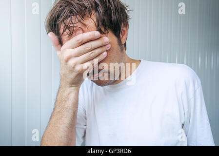 Sad and blue man covering face and crying in despair Stock Photo