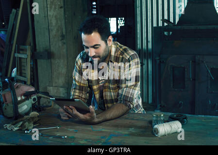 Man searching internet for instructions to repair broken chainsaw Stock Photo