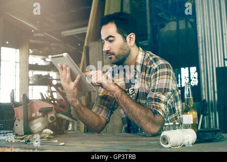 Man in workshop using digital tablet to access do-it-yourself repair instructions on internet Stock Photo