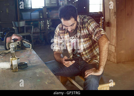 Man having beer and using smartphone during break from work Stock Photo