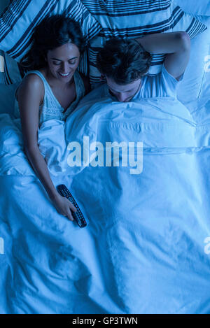 Couple watching tv together in bed Stock Photo