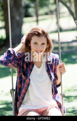 Young woman sitting on swing, portrait Stock Photo