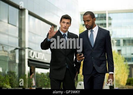 Businessmen walking and talking together outdoors Stock Photo
