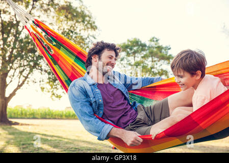 Father and son relaxing together in hammock Stock Photo