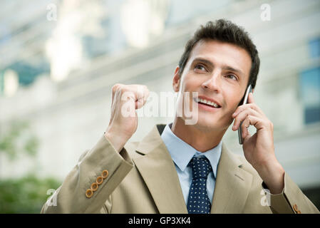 Businessman celebrating good news while talking on cell phone Stock Photo