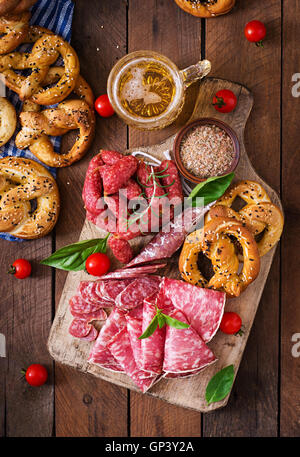 Glass of beer, pretzels and various sausages on wooden background. Oktoberfest. Top view Stock Photo