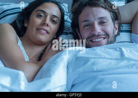 Colour portrait of nude couple in bed holding each other Stock Photo