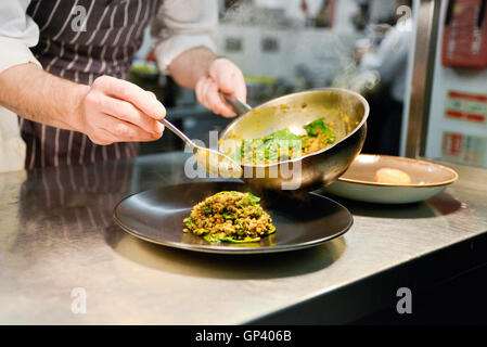 Restaurant chef placing cooked lentil dish on plate Stock Photo