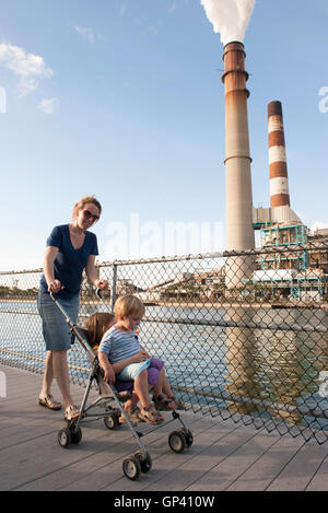 Mother pushing children in stroller near power plant Stock Photo
