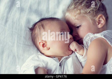 Little girl cuddling with baby brother Stock Photo