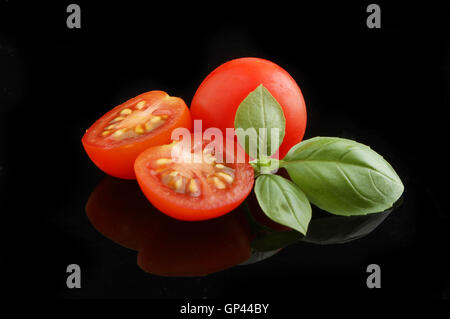 Tomatoes and basil with reflections on a black background Stock Photo