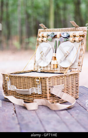 Close up of an open picnic basket over wooden table in the park. Stock Photo