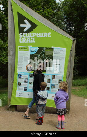 Visitors read the information board at the start of the Sculpture Trail in the Forest of Dean, Beechenhurst, Gloucesterhire Stock Photo