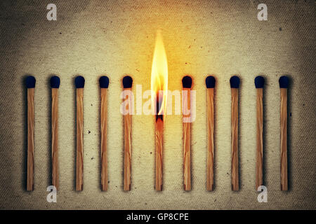 Burning match standing middle a row of whole, new matches Stock Photo