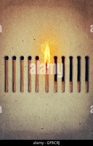 Burning match standing middle a row of whole, new matches at left and extinguished at right. Leadership concept Stock Photo