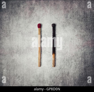 Close-up of a burnt match and a whole red match isolated on a gray background Stock Photo