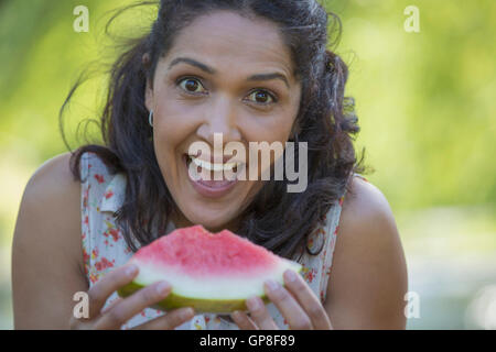 Portrait of happy Hispanic woman eating watermelon Stock Photo